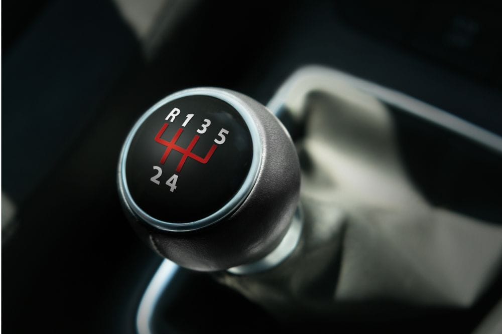 Gear shift lever of a manual transmission car with a close-up view.